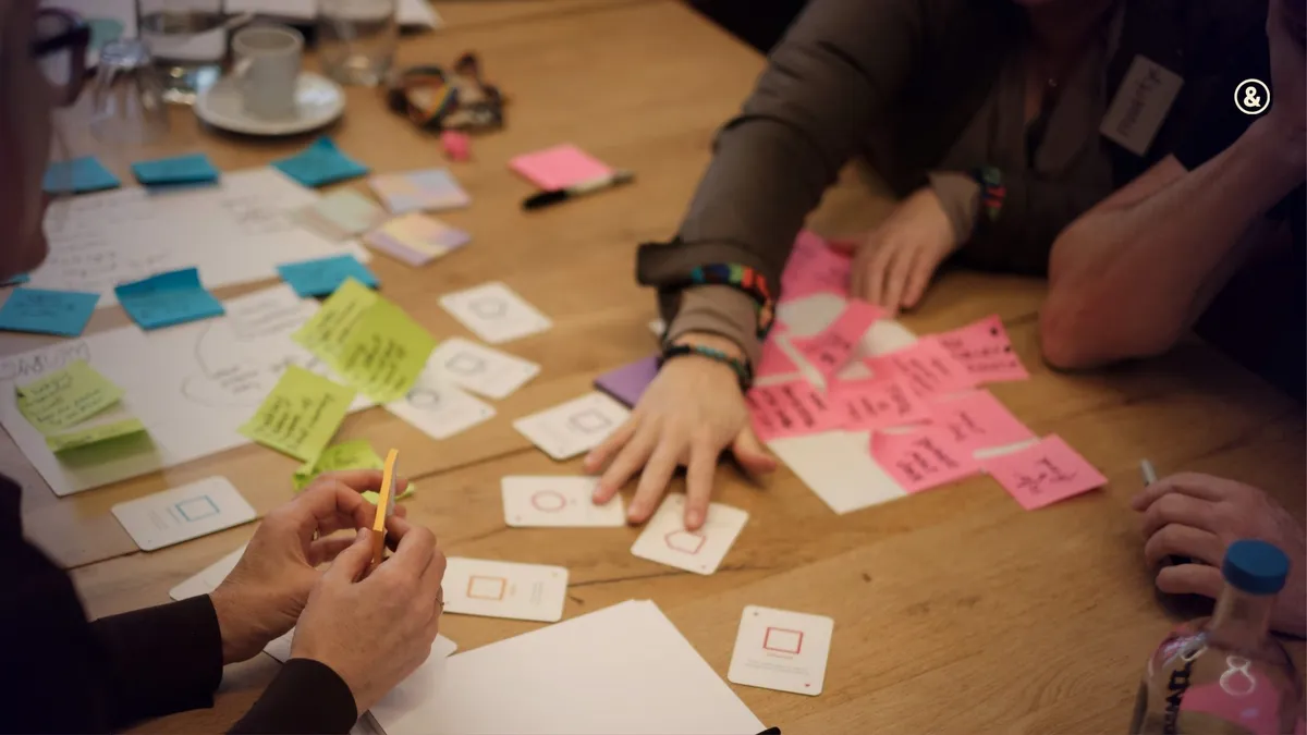 Overhead view of hands sorting colored sticky notes and cards on a table during a planning workshop.
